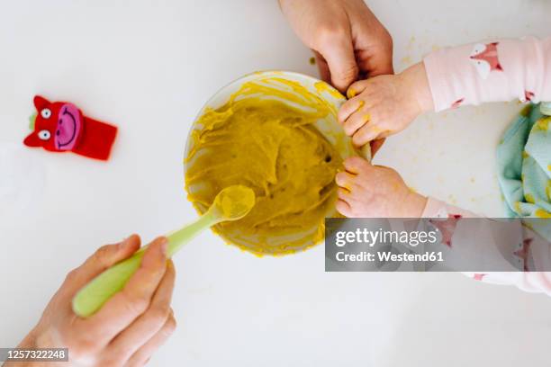 father with spoon and baby girl touching bowl with baby food - babymat bildbanksfoton och bilder