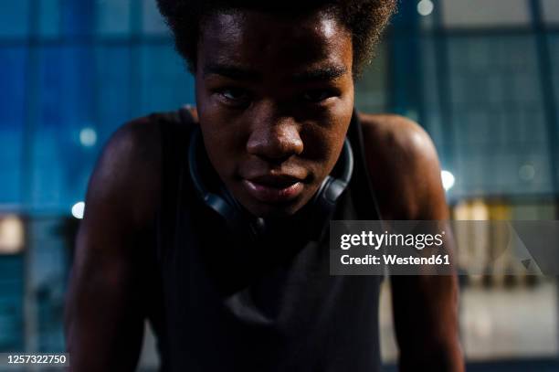 portrait of a young athletic man with headphones at dusk in city - young athlete stock pictures, royalty-free photos & images