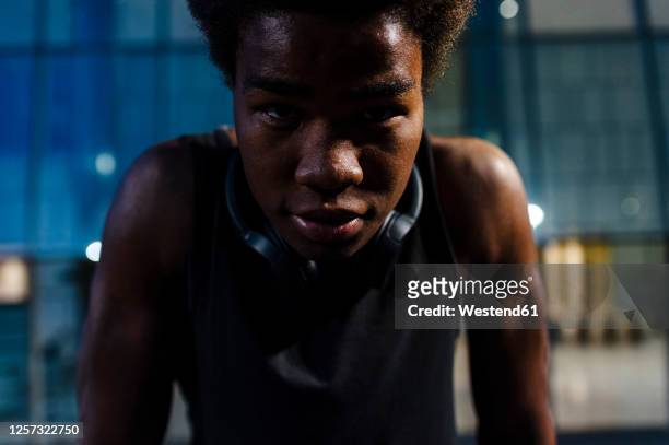 portrait of a young athletic man with headphones at dusk in city - inclinar se pose imagens e fotografias de stock