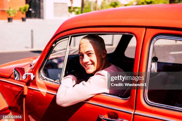 portrait of happy teenage boy sitting in vintage car looking out of window - boy with car stock pictures, royalty-free photos & images