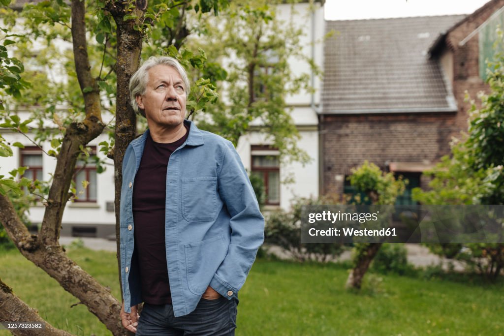 Senior man standing in a rural garden looking up