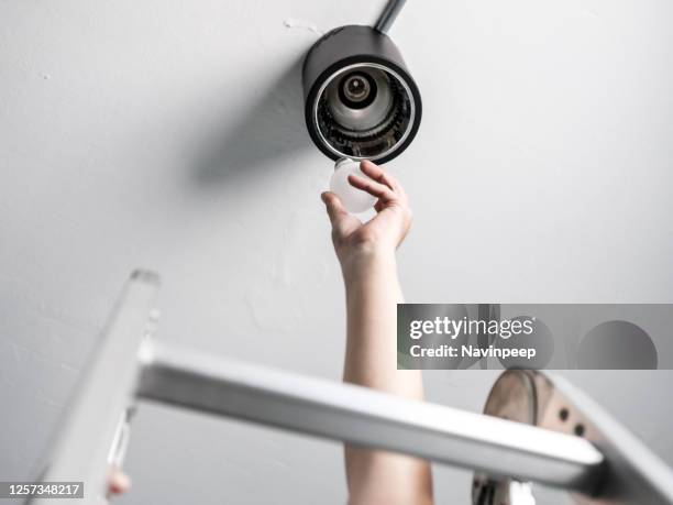 changing light bulb on a ladder, ant's eye view - lampje-vervangen stockfoto's en -beelden