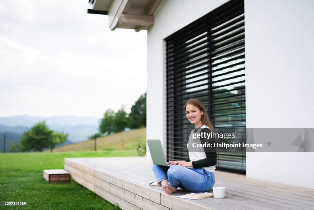 Young student with laptop learning outdoors at home, homeschooling concept.