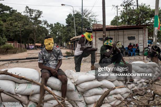 Protesters sit on top of sandbag barricades as they block the road to opposition leader Ousmane Sonko's house in Ziguinchor, Senegal on May 22, 2023....