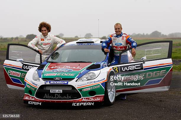 In this handout image supplied by Castrol, Moto GP rider Marco Simoncelli of Italy poses with driver Mikko Hirvonen of Finland during a one-off test...