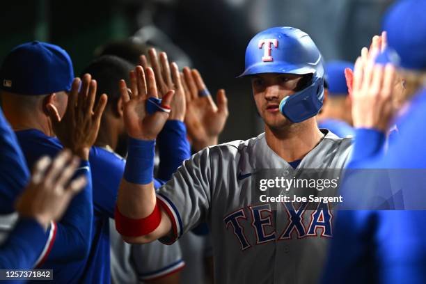 Josh Jung of the Texas Rangers celebrates hitting a home run in the dugout with his teammates during the ninth inning of the game between the Texas...