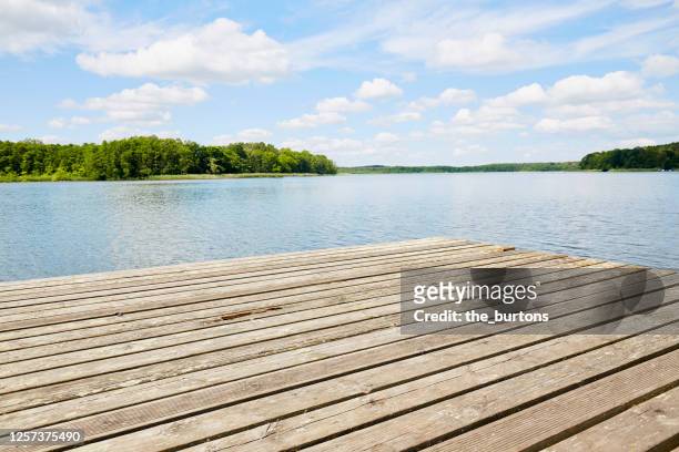 jetty at idyllic lake against blue sky and clouds - passerella di legno foto e immagini stock