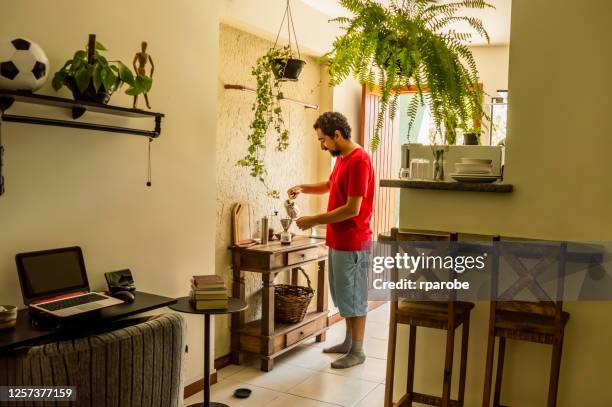 ein mann in blauen shorts, die kaffee in der küche machen - blaue shorts stock-fotos und bilder