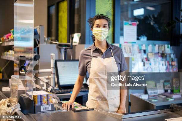 woman working at a supermarket during pandemic - supermarket cashier stock pictures, royalty-free photos & images