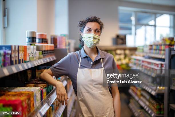 woman working in grocery shop during pandemic - essenzielle berufe und dienstleistungen stock-fotos und bilder