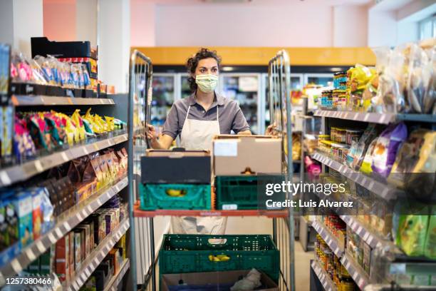 female staff working in grocery store re-stocking goods - shop assistant stock pictures, royalty-free photos & images