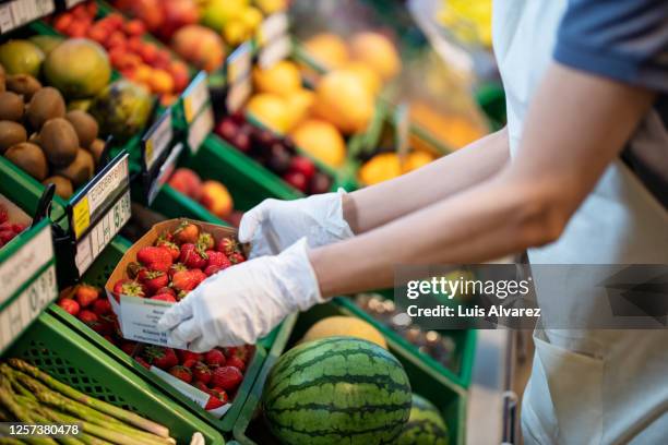 store assistant at supermarket arranging fruits on shelve - obst stock-fotos und bilder