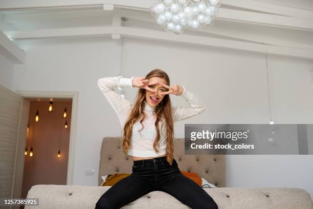 sitting on the edge of bed showing the peace sign - beautiful romanian women stock pictures, royalty-free photos & images