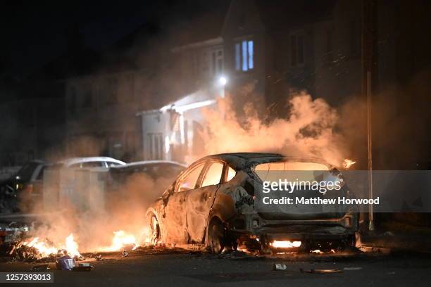 An automobile burns on Highmead Road during unrest following a serious road crash earlier on Snowden Road on May 23, 2023 in Cardiff, Wales. Riot...
