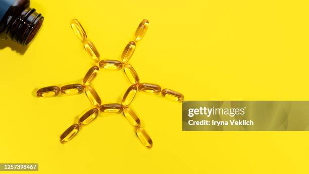 yellow pills forming shape to sun. capsules with omega 3. - 3 d letters stock-fotos und bilder