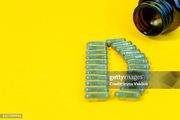 yellow pills forming shape to d alphabet and vitamin d bottle on yellow background. - vitamins and minerals imagens e fotografias de stock