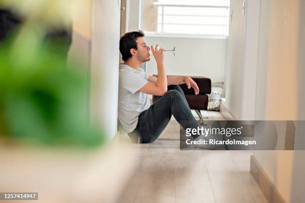 latino man sitting in a hallway of his living room having a glass of wine - alcohol abuse stock pictures, royalty-free photos & images