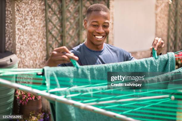 young man hanging out washing to dry in garden - man hanging stock pictures, royalty-free photos & images