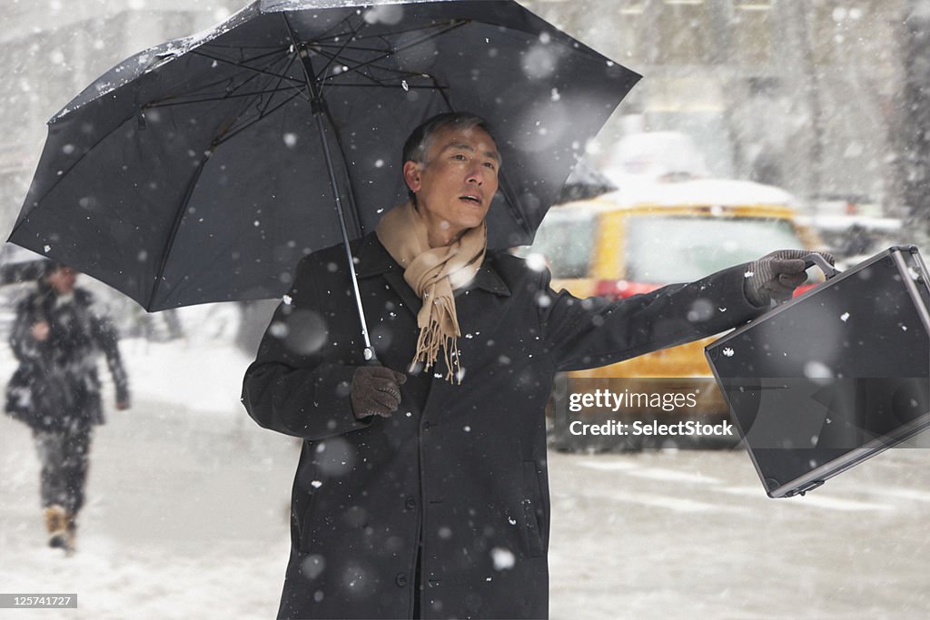 Mid-age man Hailing a cab in the snow