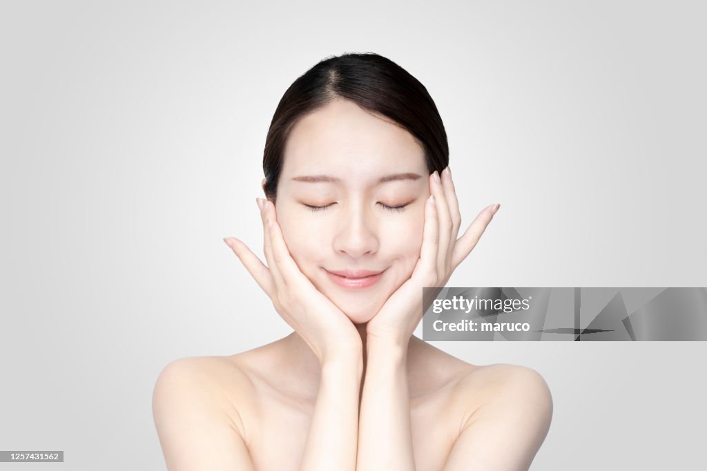 Asian young woman touching face with relaxed expression