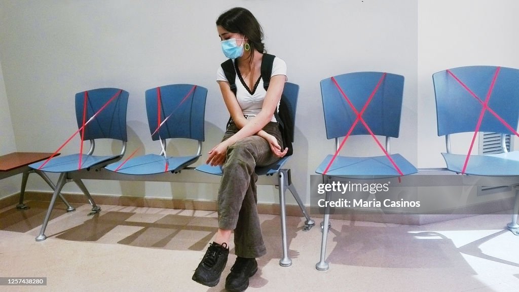 Waiting room, security rules. Young girl sitting, waiting with arms crossed, wearing protective face mask, in coronavirus time