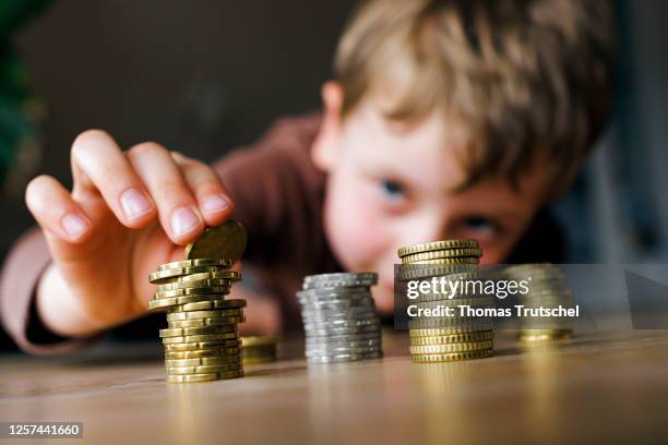 Symbolic photo on the topic of saving in childhood. A five-year-old boy stacks loose change on a table on May 19, 2023 in Berlin, Germany.