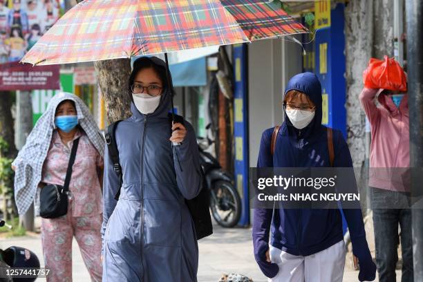 This photo taken on May 22, 2023 shows a woman carrying an umbrella to shield herself from the sun on a street in Hanoi.