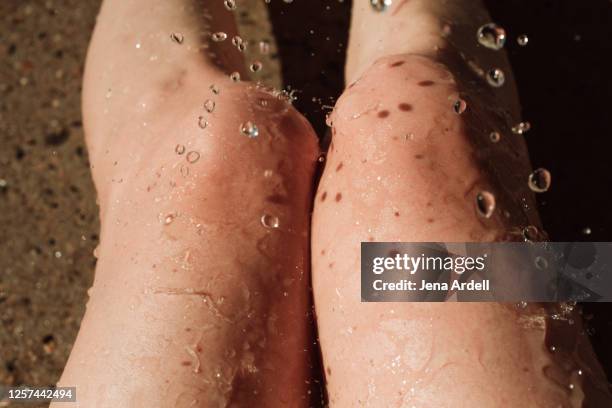 water splashing on woman's knees, bare legs summertime - legs in water fotografías e imágenes de stock