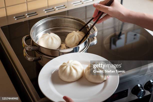 woman taking out fresh baozi chinese steamed buns from the metal steamer at home - hot arab women stock pictures, royalty-free photos & images