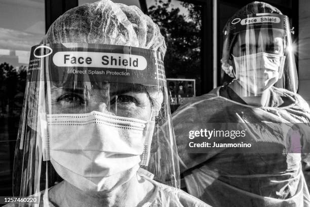 dramatic black and white image of tired, overworked, exhausted health care workers outside the hospital - real life hero stock pictures, royalty-free photos & images