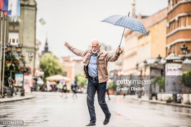 un anciano alegre corriendo bajo la lluvia. - hombre mojado fotografías e imágenes de stock