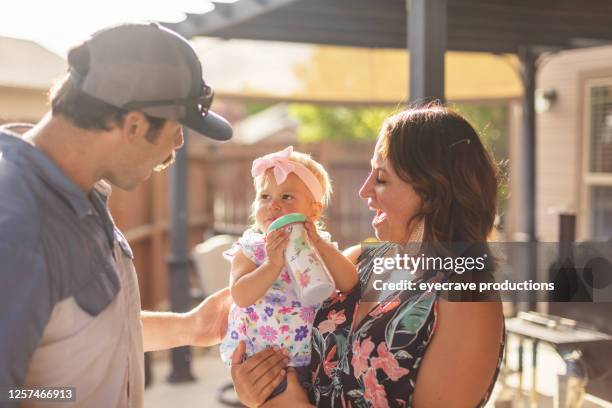millennial eltern mit mutter halten weibliche kleinkind tochter im freien auf patio - mittelstand stock-fotos und bilder