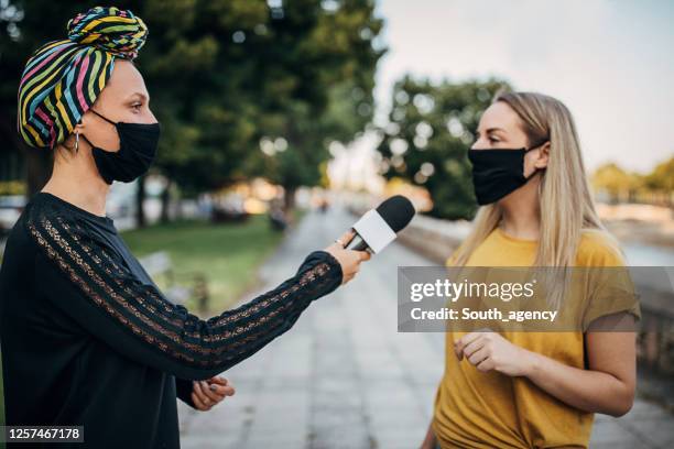 junge frau antwortet journalistischen frauen auf der straße während coronavirus pandemie - woman interview stock-fotos und bilder