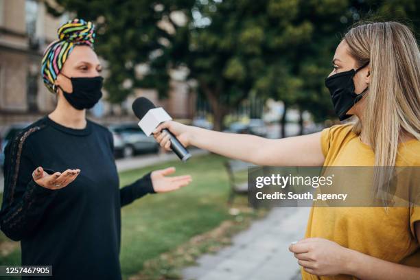 frau antwortet journalisten auf der straße während coronavirus-pandemie - interview stock-fotos und bilder