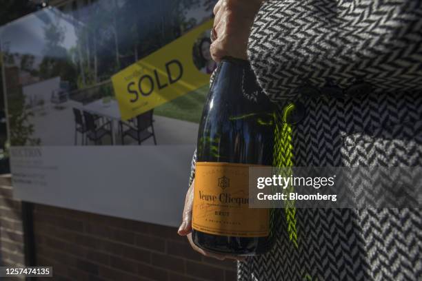 The owner of a property holds a champagne bottle in front of a sold sign following an auction in Sydney, Australia, on May 20, 2023. In Australia,...