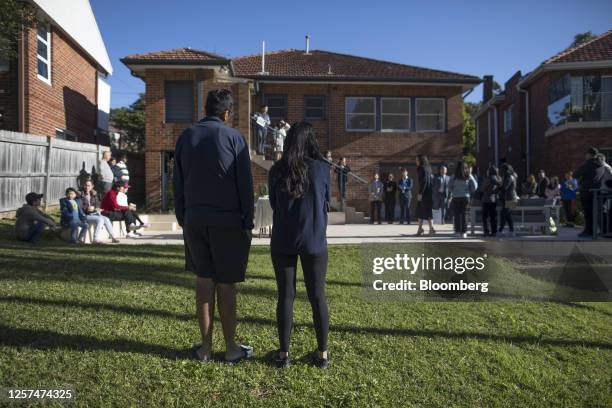 People stand outside during an auction of a property in Sydney, Australia, on May 20, 2023. In Australia, it's never been harder for people to get on...