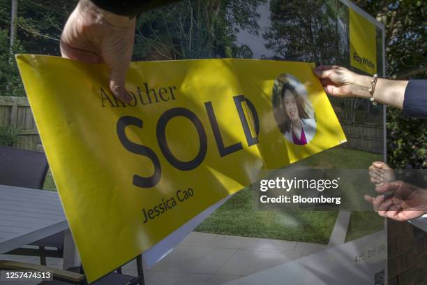 Real estate agent pastes a sold sticker onto a sign following an auction of a property in Sydney, Australia, on May 20, 2023. In Australia, it's...