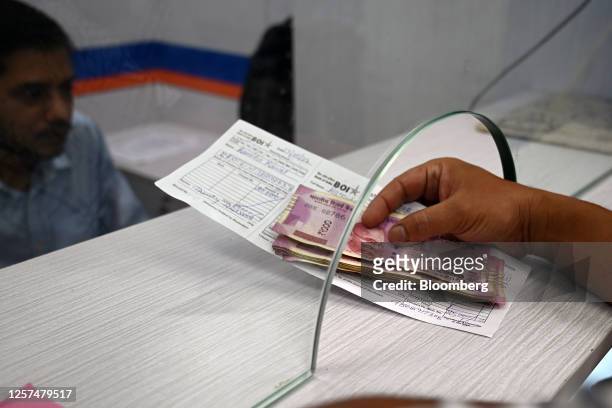 Customer deposits 2,000 rupee banknotes at a bank in New Delhi, India, on Tuesday, May 23, 2023. India withdrawing its highest value currency notes...