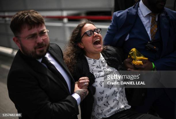Security guards escort away a climate activist during a demonstration outside ExCeL, in London, during the multinational oil and gas company Shell...