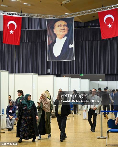 Turkish voters living in Germany walk below a portrait of Mustafa Kemal Ataturk, founding father of the Republic of Turkey, at a polling station set...