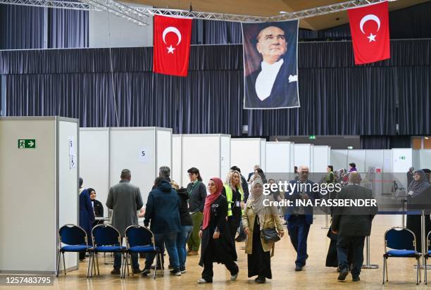 Turkish voters living in Germany walk below a portrait of Mustafa Kemal Ataturk, founding father of the Republic of Turkey, at a polling station set...