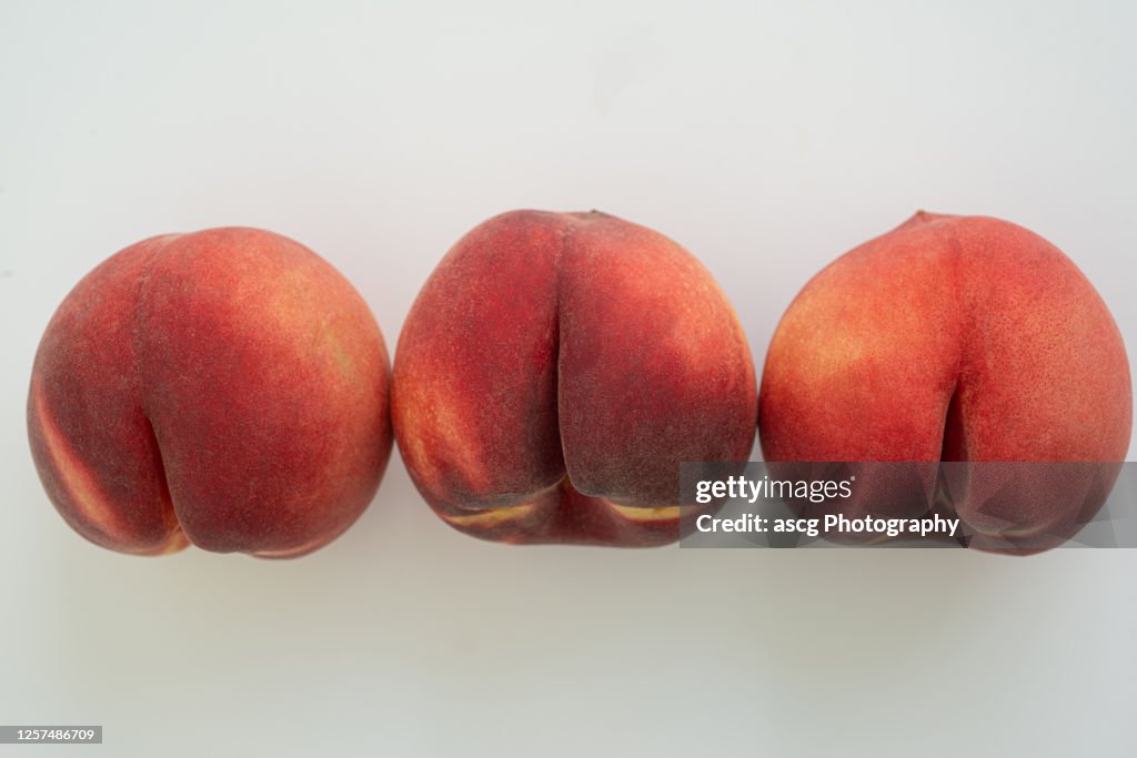 A row of white peaches on white surface