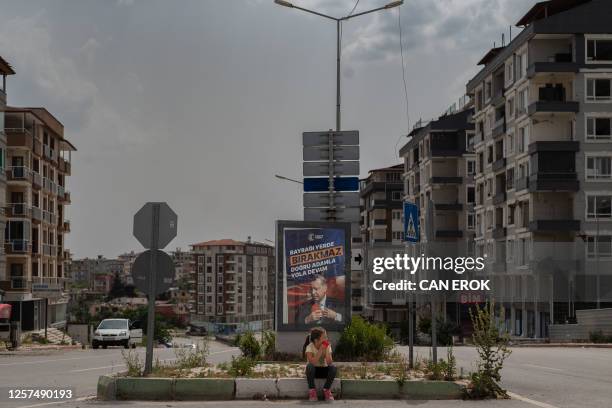 Girl sits in front of an election poster of Turkish President Recep Erdogan in Hatay, on May 22 one of the cities worst affected by the devasting...