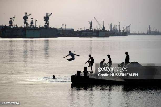 Youths swim in the Shatt al-Arab waterway, formed at the confluence of the Euphrates and Tigris rivers, in Iraq's southern city of Basra, on May 23,...