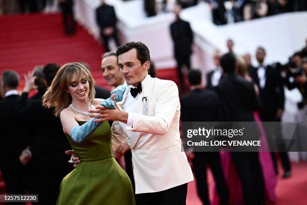 British actor Rupert Friend dances with US actress Maya Hawke as they arrive for the screening of the film "Asteroid City" during the 76th edition of...