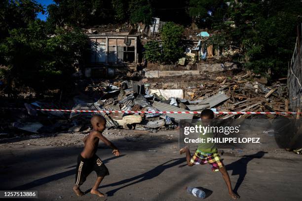 Children play football with a plastic bottle in front of demolished buildings in the shantytown of "Talus 2" district in Koungou, during its...