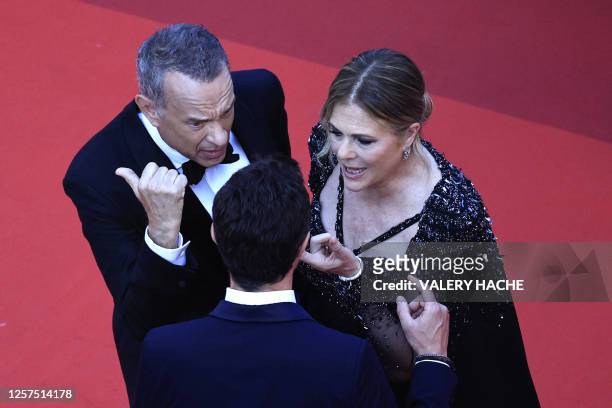 Actor Tom Hanks and US actress Rita Wilson speak with a staff member as they arrive for the screening of the film "Asteroid City" during the 76th...