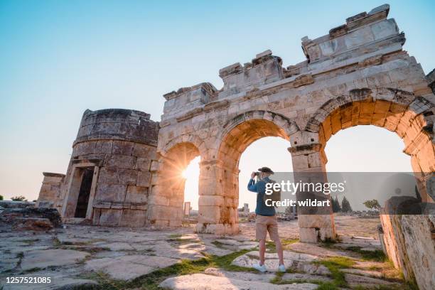 traveller tourist is taking photo of frontinus gate in ancient ruins in hierapolis at sunset , pamukkale - hierapolis stock pictures, royalty-free photos & images