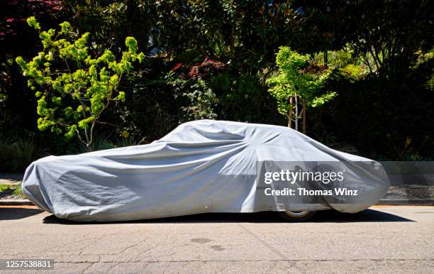 covered car on a street - covered car stock-fotos und bilder
