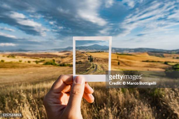 personal perspective of polaroid picture overlapping the tuscany landscape, italy - parte del cuerpo humano fotos fotografías e imágenes de stock
